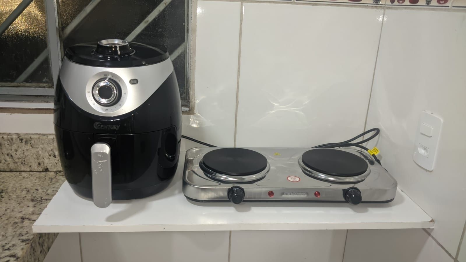 Cozinha com cafeteira e fogão em bancada branca.