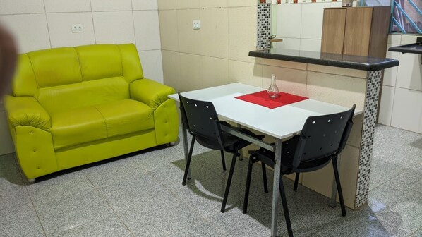A small kitchenette with a white countertop and a red placemat on a table with two chairs.