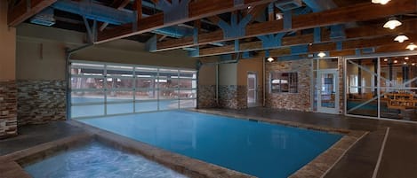 Ein Hallenbad mit Whirlpool, Steinwänden und Blick ins Freie.