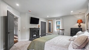 Un dormitorio con cama, chimenea, televisor y ventana.