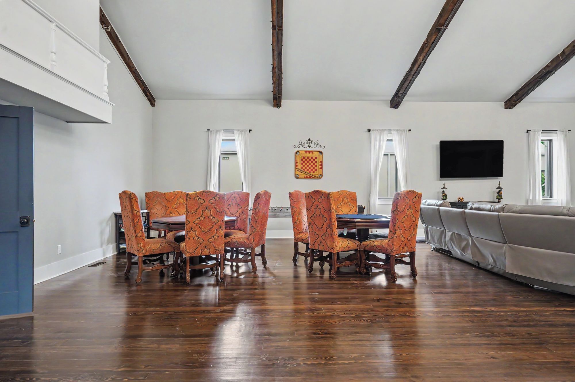 A dining area with a wooden table and chairs, a flat-screen TV, and a sofa.