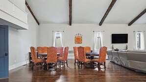 Un comedor espacioso con una mesa larga y sillas a juego, un televisor montado en la pared y un amplio ventanal con cortinas.