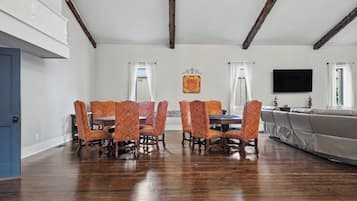 A dining area with a wooden table and chairs, a flat-screen TV, and a sofa.