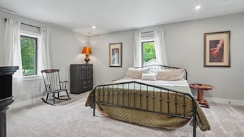 A bedroom with a bed, dresser, chair, lamp, and artwork.