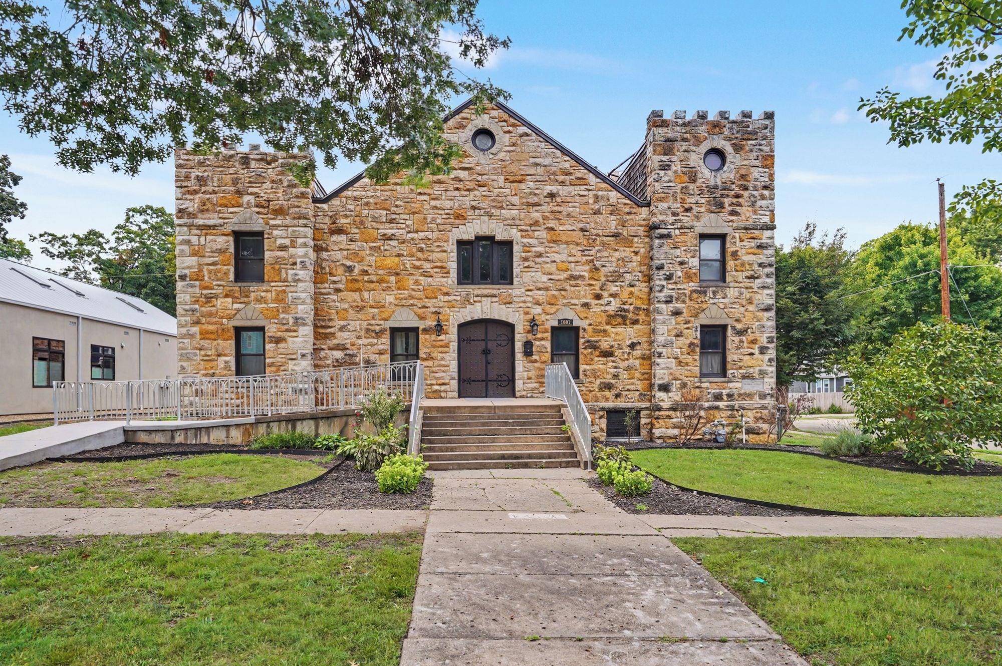 A stone building with a central entrance, a small porch, and a flagpole.