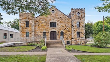 A stone building with a central entrance, a small porch, and a flagpole.
