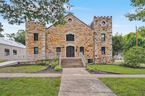 A stone building with a central entrance, a small porch, and a flagpole.