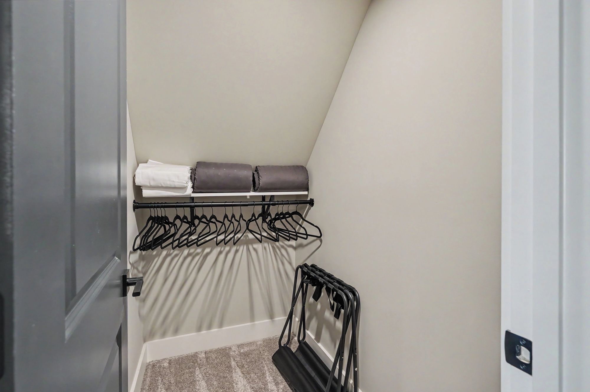 A closet with hanging space and shelves, containing folded clothes and a shoe rack.