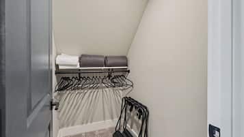 A closet with hanging space and shelves, containing folded clothes and a shoe rack.