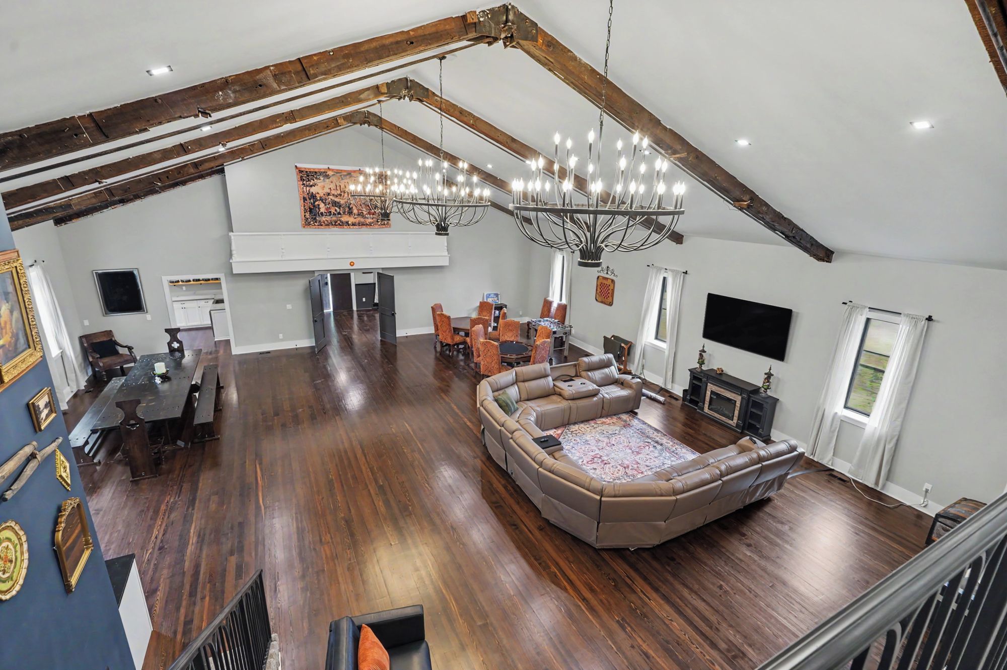 A spacious loft with high ceilings, exposed beams, a large seating area, and a fireplace.
