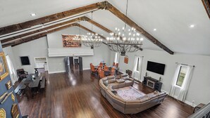Un loft espacioso con techos altos, vigas de madera a la vista, un amplio espacio para sentarse y un comedor.