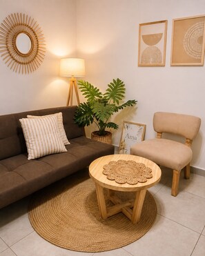 A living room with a brown sofa, a round wooden coffee table, a potted plant, a lamp, and framed artwork on the wall. - Guest apartment in an unbeatable location in Palermo (Buenos Aires)
