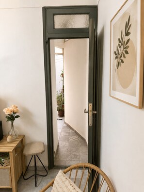 Una puerta que da a un pasillo con una planta en maceta y un cuadro en la pared.
