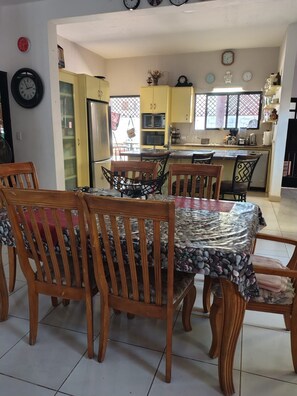 A dining area with a table covered in a patterned tablecloth, surrounded by wooden chairs. - Spacious 2-Bedroom Ground-Floor Home in Downtown Loreto (Loreto)