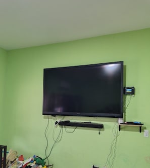 A television mounted on a wall with a stand below it, connected to various cables and a power strip. - Spacious 2-Bedroom Ground-Floor Home in Downtown Loreto (Loreto)