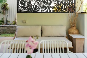 A bedroom with a bed, two pillows, a nightstand, a vase with branches, and a view of the outdoors. - Cedar Cove - Tropical Escape near Palm Cove Beach (Palm Cove)