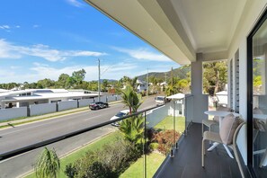 Ein Balkon mit Blick auf eine Straße, Häuser und Grünflächen.