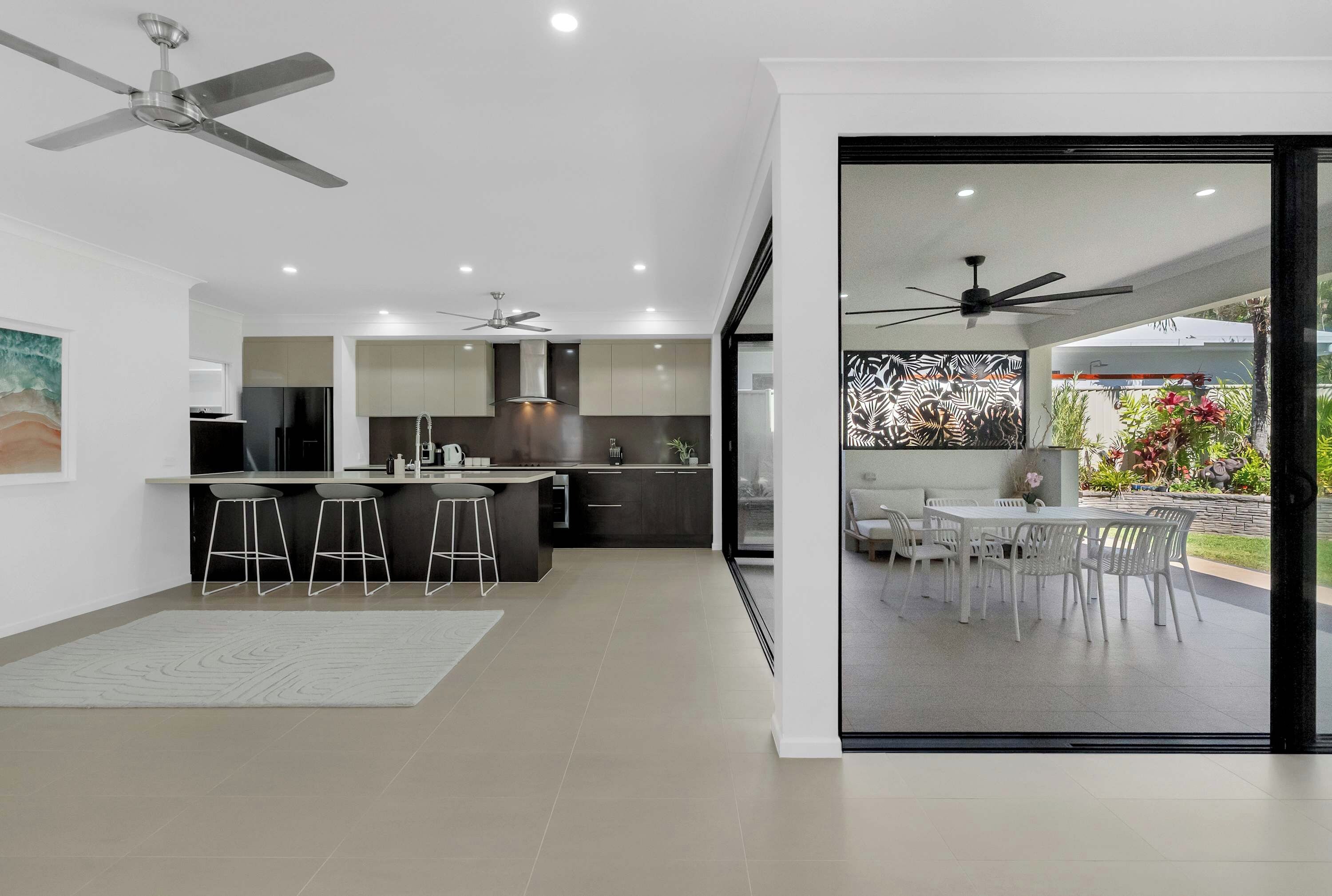 A modern kitchen with a central island, bar stools, and a dining area with a table and chairs.
