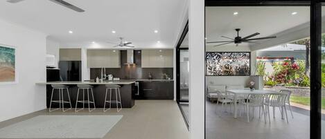 A modern kitchen with a central island, bar stools, and a dining area with a table and chairs.