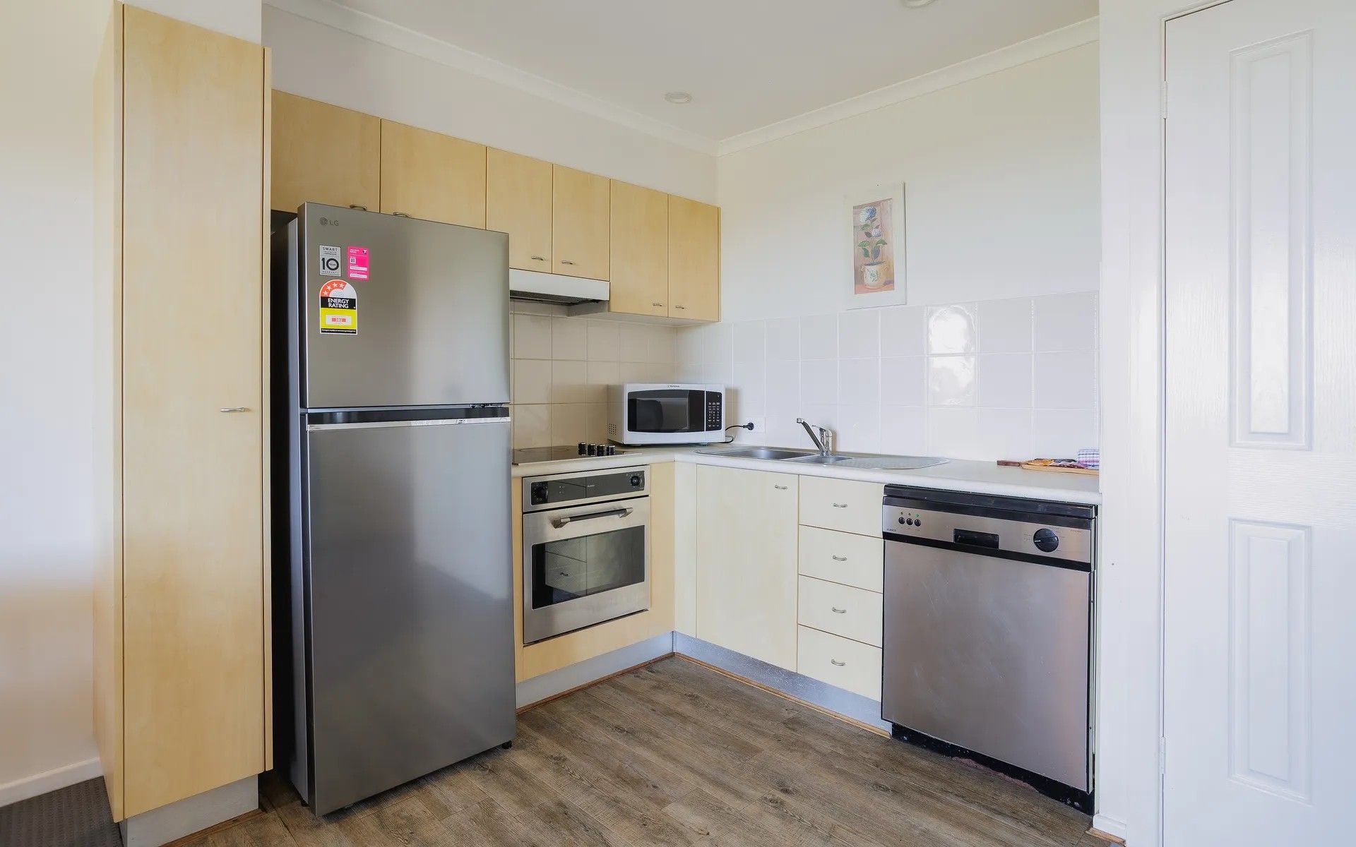 Una cocina compacta con refrigerador de acero inoxidable, microondas, horno y lavavajillas.