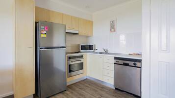 Una cocina compacta con refrigerador de acero inoxidable, microondas, horno y lavavajillas.