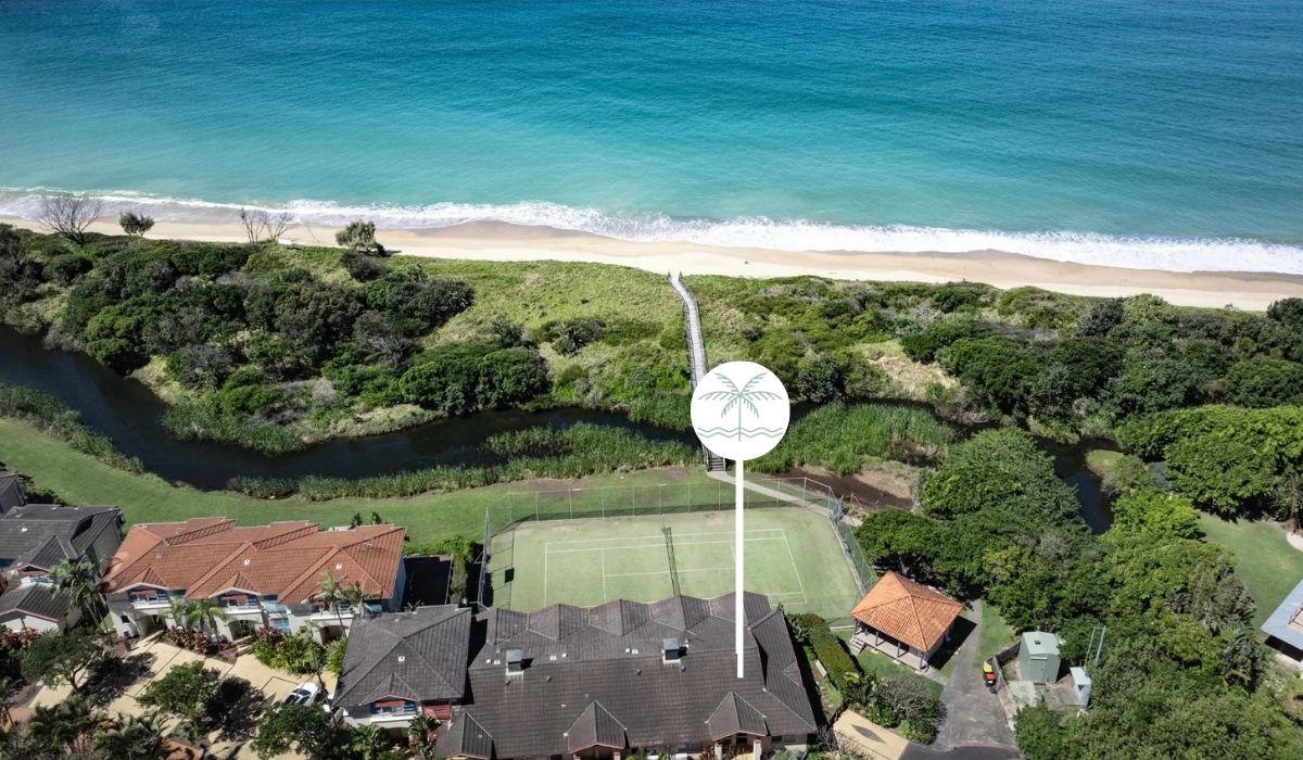 Un quartier résidentiel avec des maisons, un court de tennis et une plage.
