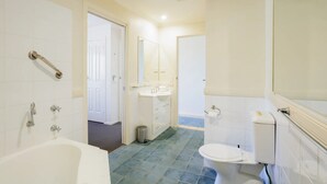 Et badeværelse med badekar, toilet og håndvask.