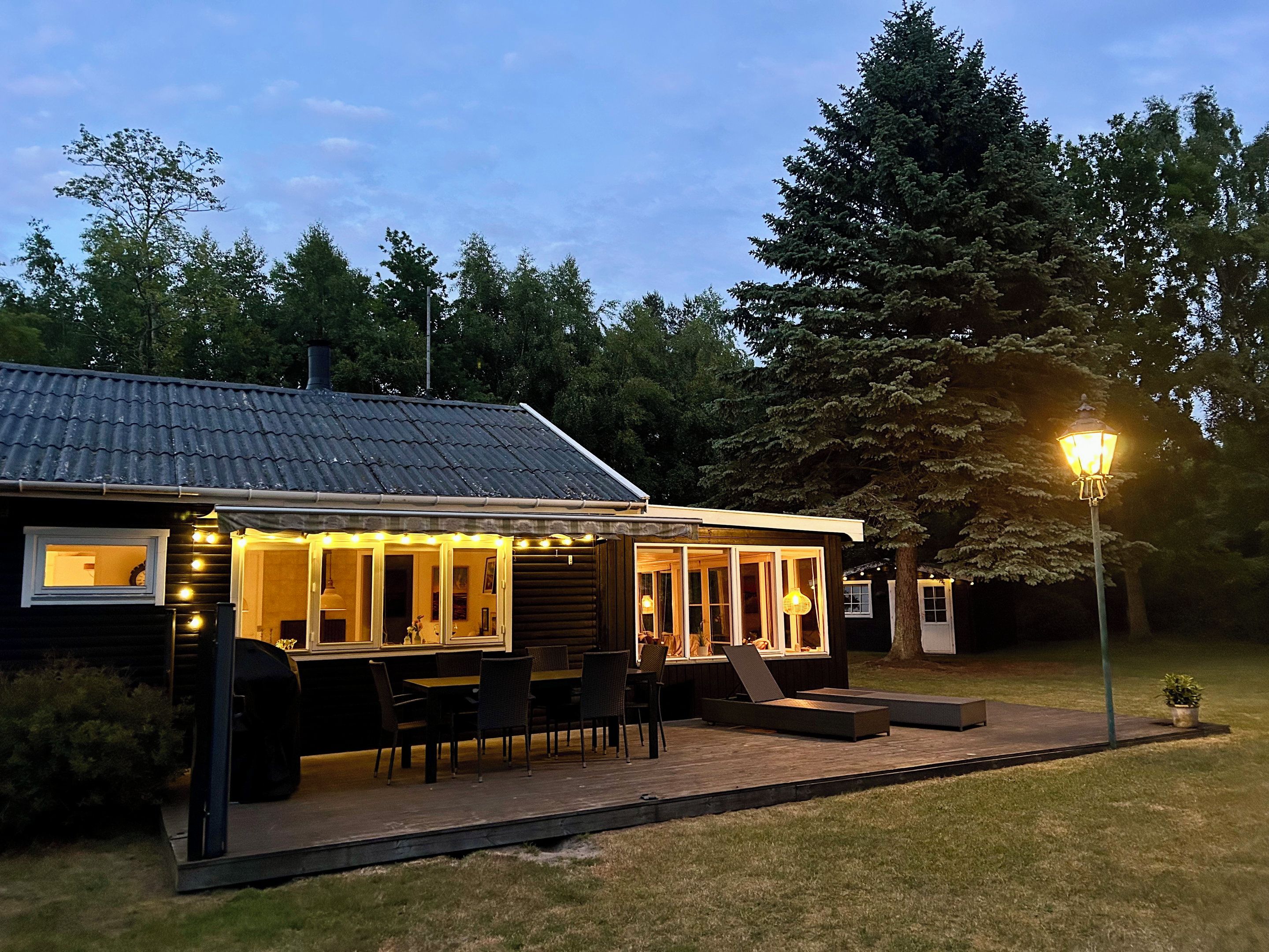 A modern house with a covered patio, outdoor seating, and a well-lit entrance.