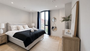 A modern bedroom with a bed, bedside tables, a mirror, and a sign. - Downtown Manchester Townhouse w/ Garden & Modern (Greater Manchester)
