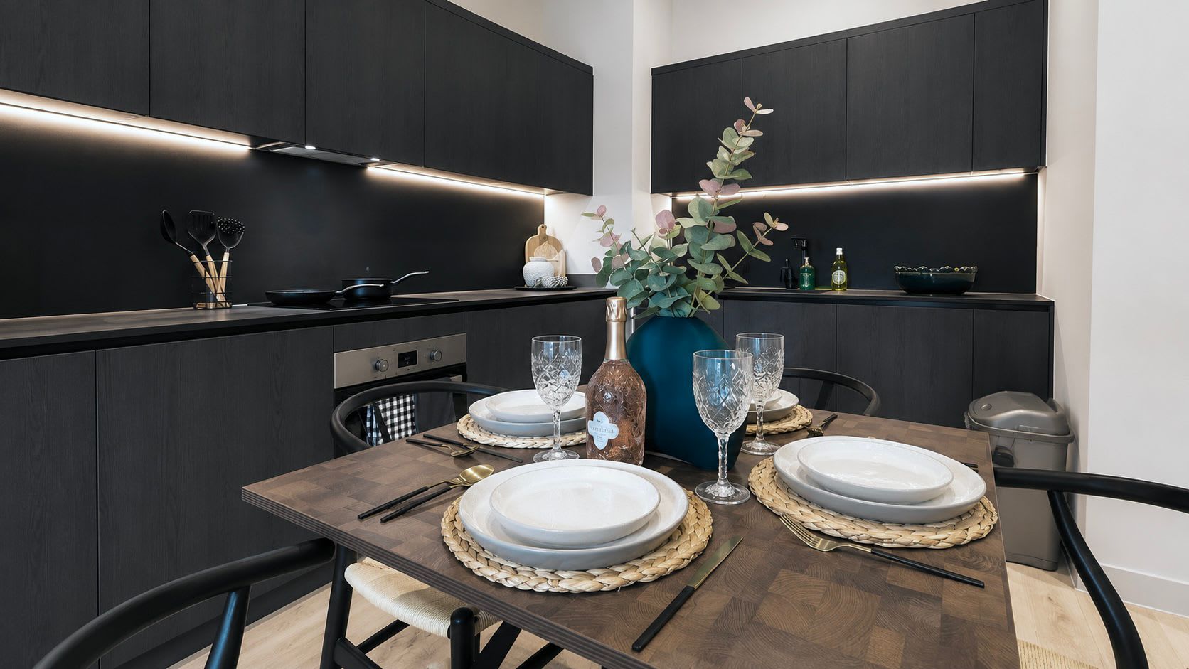 A modern dining area with a dark wood table set for four, featuring woven placemats and white plates.