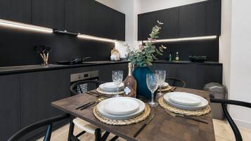 A modern dining area with a dark wood table set for four, featuring woven placemats and white plates.