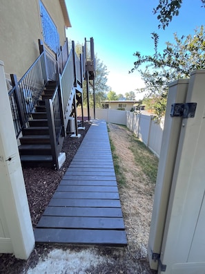 A wooden deck leading to a house with a metal staircase and a decorative metal gate. - Convenient and private studio with relaxing deck (Holladay)