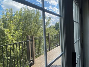 A balcony with a metal railing and wooden posts, overlooking a dense green forest. - Convenient and private studio with relaxing deck (Holladay)
