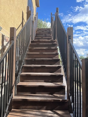 A wooden staircase with metal railings leading to a building entrance. - Convenient and private studio with relaxing deck (Holladay)