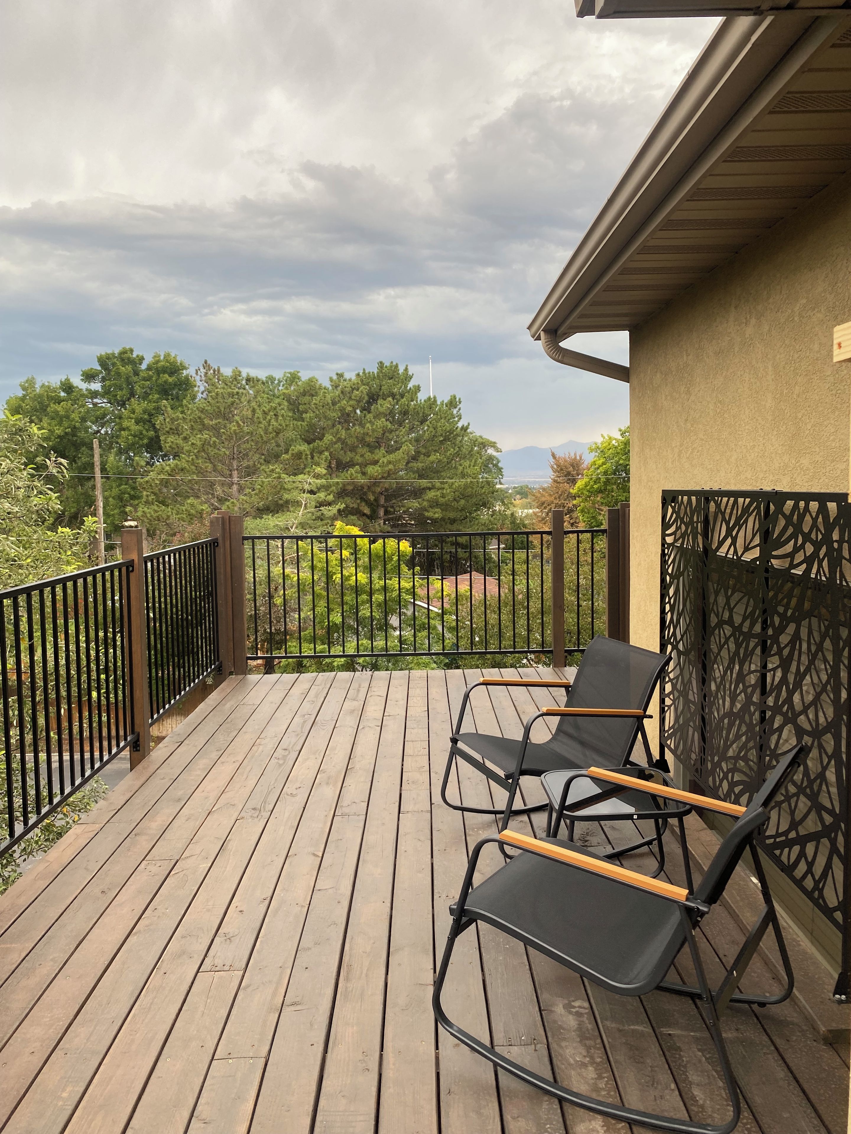 Eine Holzterrasse mit zwei Liegestühlen und einem Metallzaun.