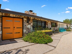 A modern building with a stone facade, a large orange door, and a landscaped garden area. - Custom Mid Century! Game Room, Sleeps 15.  4 King Rooms. Theatre Room. (Mesa)