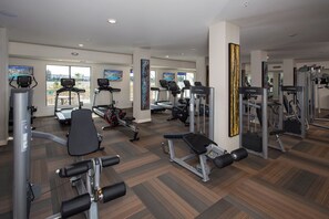 Ett gym med löpband, styrketräningsmaskiner och en spegel.