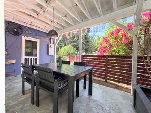 Une terrasse extérieure avec une table et des chaises, un ventilateur et un luminaire décoratif.