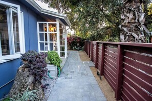 Un chemin menant à une maison à l’extérieur bleue et aux fenêtres blanches.