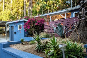 A blue house with a small porch, surrounded by various plants and trees. - Canyon Hill Retreat: Washer, Dryer, Full Kitchen, Patio, Private (Los Angeles)