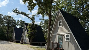 Een rij kleine, gelijkvloerse hutten met een grindpad, omringd door bomen.