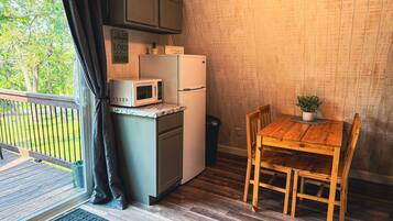 Cocina compacta equipada con microondas, refrigerador y mesa de madera con sillas.
