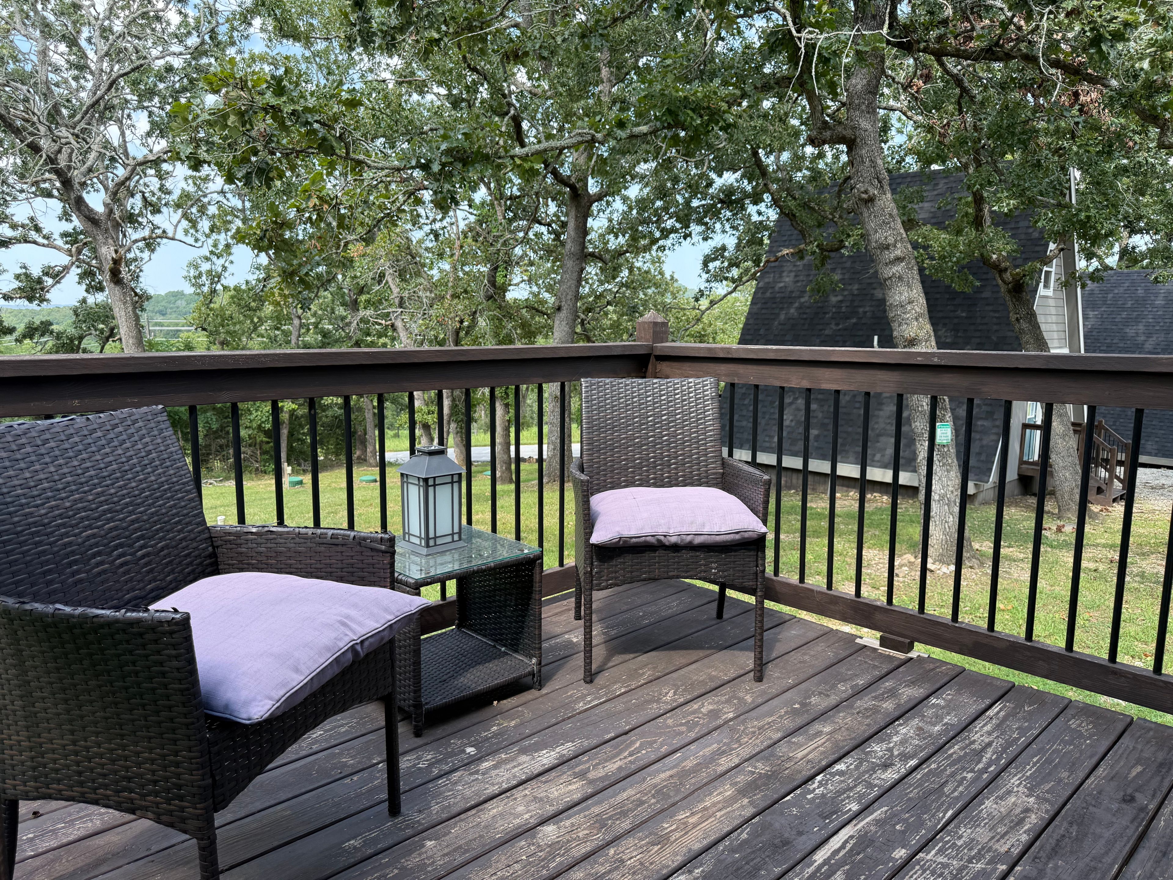 A wooden deck with wicker furniture and a lantern.