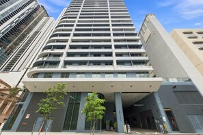 A modern high-rise building with a prominent entrance and multiple balconies. - Modern Miami Studio | 801B | Pool Hot Tub & Gym (Miami)