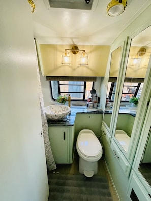 Ein kleines Badezimmer mit Toilette, Waschbecken und Spiegel.