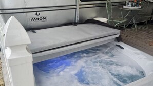 Een hottub met uitzicht op de lucht, een witte buitenkant en een logo aan de zijkant.