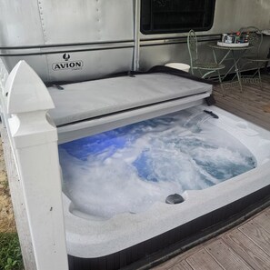 Ein Whirlpool mit freiem Blick zum Himmel durch das Wasser, einer weißen Außenwand und einem Logo an der Seite.