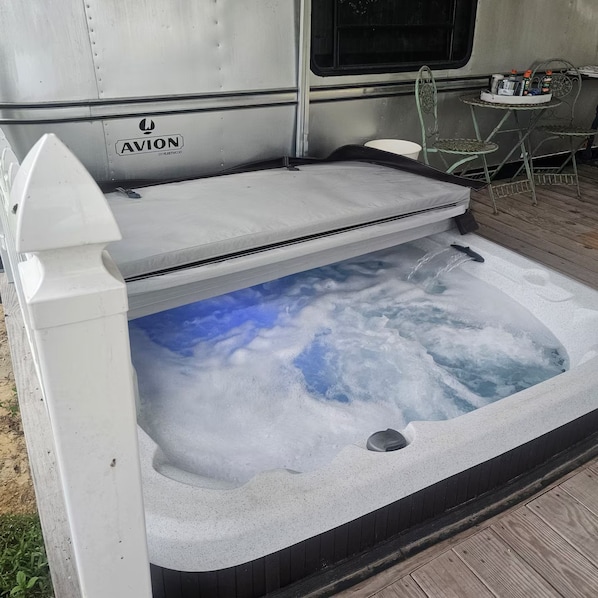 A hot tub with a clear view of the sky through the water, a white exterior, and a logo on the side.