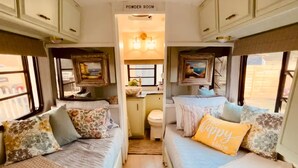 Een gezellig RV-interieur met twee bedden, een gastentoilet en een kleine keuken.