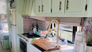 Een keuken met lichtgroene kastjes, een roestvrijstalen fornuis en een raam met uitzicht.